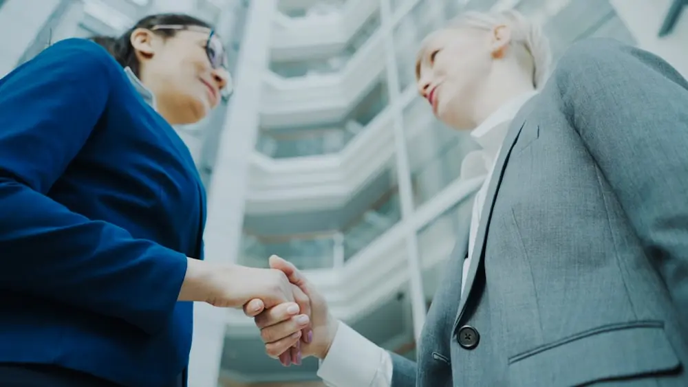 Two property professionals shaking hands outside an office building