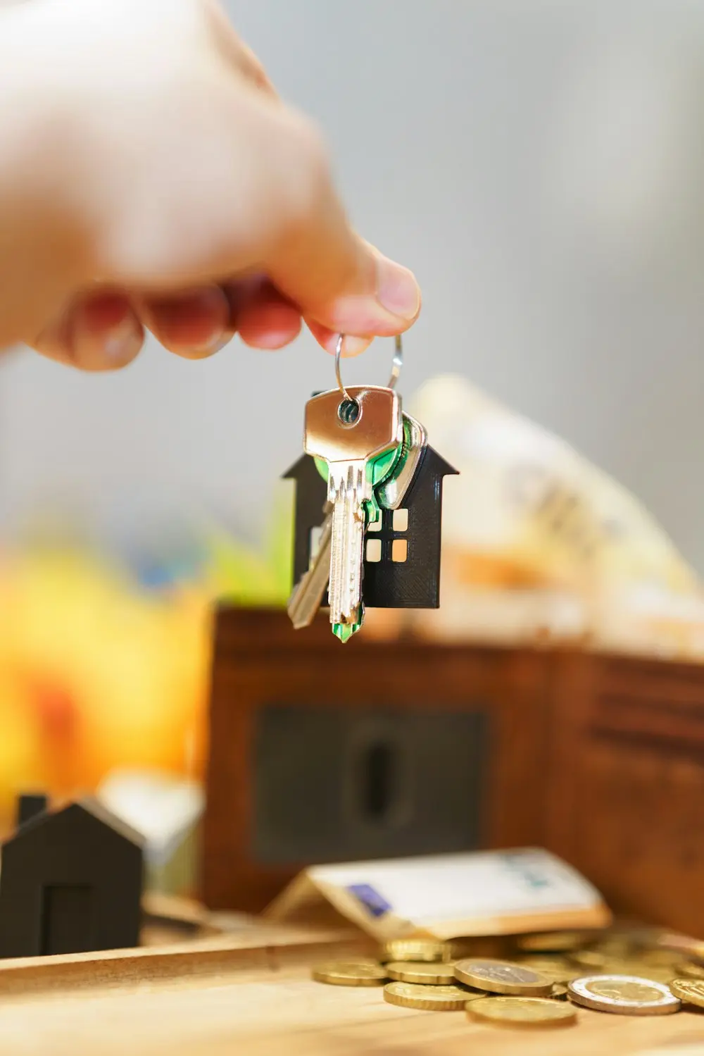 Hand holding house keys with a house-shaped keyring
